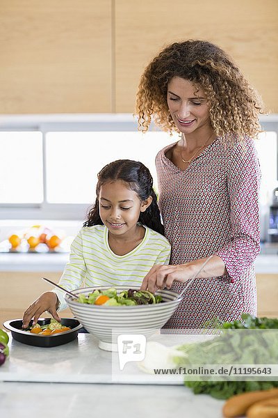 Happy young woman with daughter in kitchen