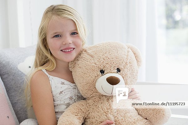 Porträt eines süßen Mädchens mit Teddybär auf dem Bett