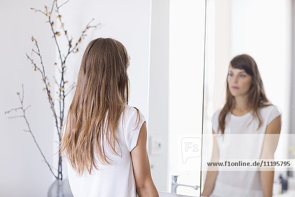 Frau schaut sich selbst im Spiegel an