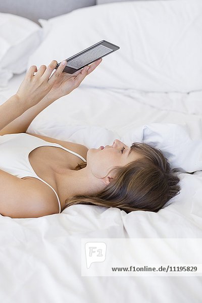 Woman lying on the bed using a digital tablet