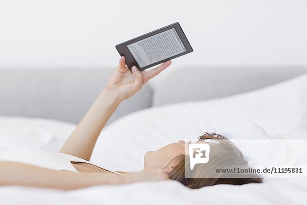 Woman lying on the bed using a digital tablet