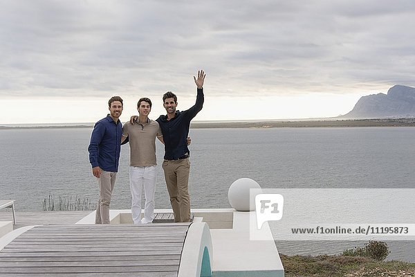 Porträt von drei glücklichen männlichen Freunden am Seeufer