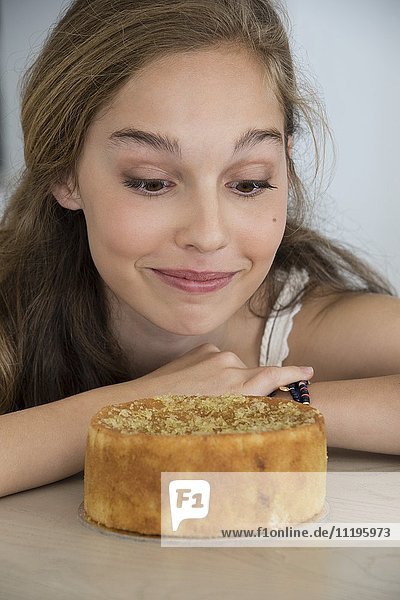 Beautiful teenage girl looking at cake
