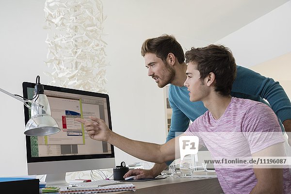 Zwei junge Geschäftsleute arbeiten zusammen am Computer in einem Büro.