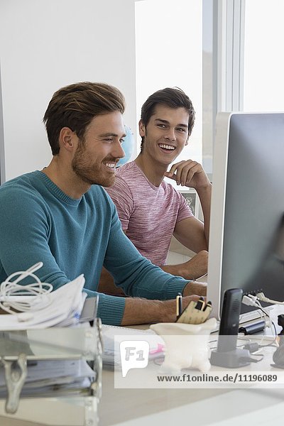 Happy young businessmen working together on computer in an office