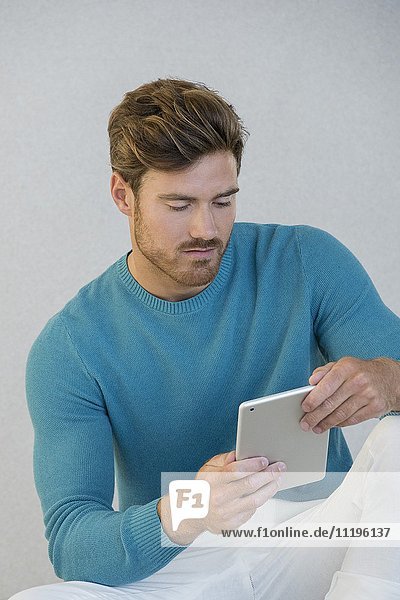Junger Mann mit einem digitalen Tablett zu Hause