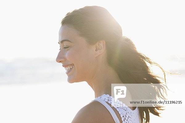 Schöne junge Frau  die am Strand lächelt.