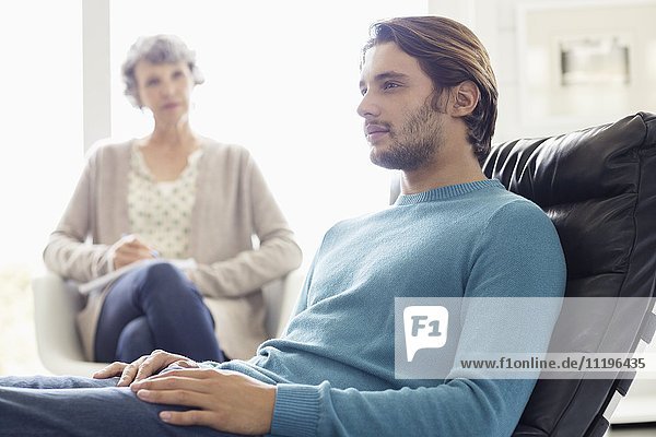 Serious mother and son sitting together in living room