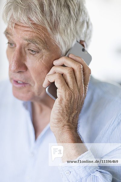 Ein älterer Mann  der auf dem Handy spricht.