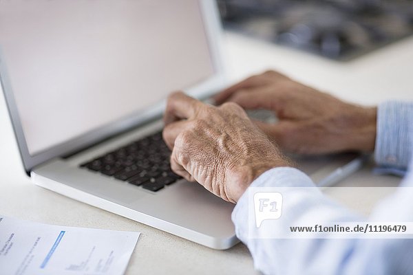 Senior Mann bezahlt Rechnungen online auf dem Laptop