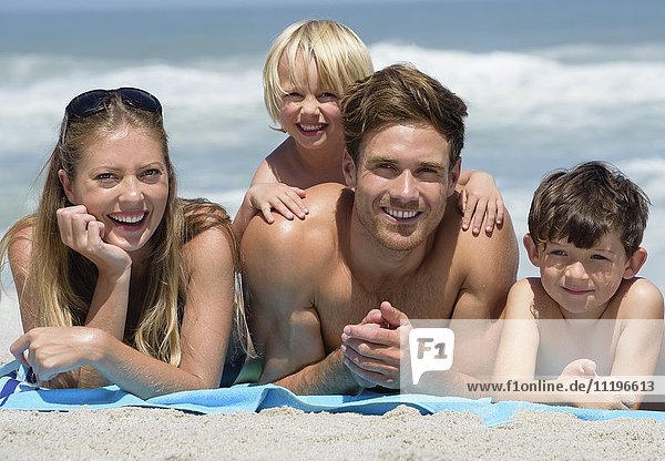 Porträt einer glücklichen Familie am Strand liegend