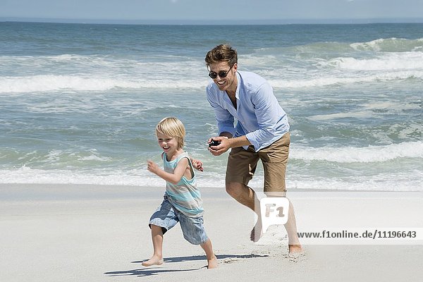 Junger Mann spielt mit seinem Sohn am Strand.
