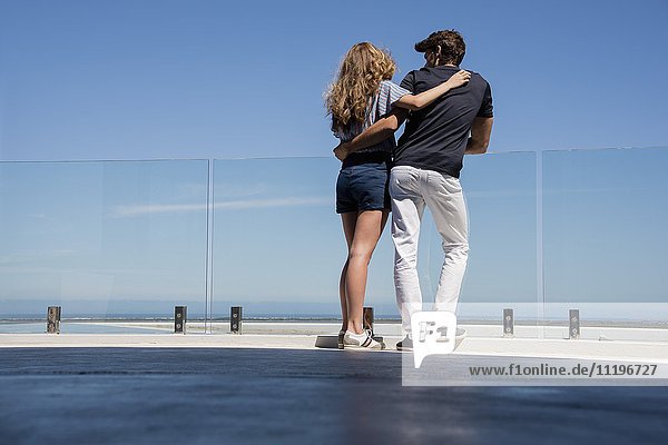 Young couple standing by infinity pool in resort