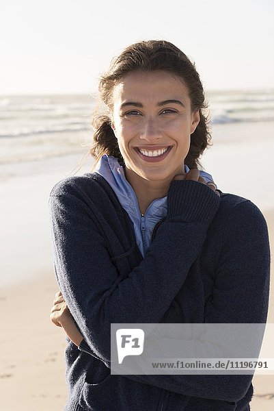Porträt einer glücklichen schönen Frau  die am Strand steht