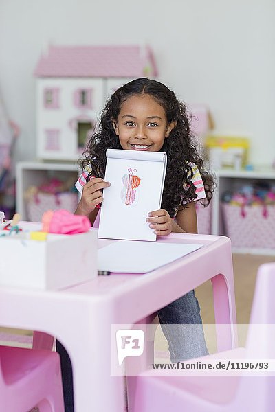 Porträt eines glücklichen kleinen Mädchens mit ihrer Zeichnung