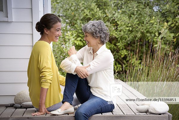 Glückliche Mutter im Gespräch mit ihrer erwachsenen Tochter auf der Veranda