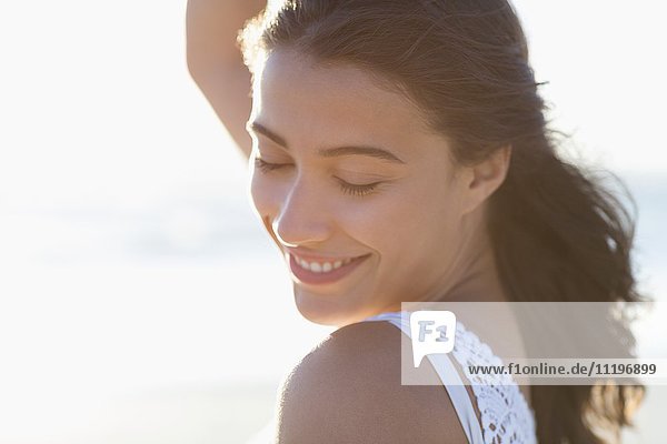 Nahaufnahme einer schönen jungen Frau  die am Strand lächelt.