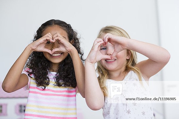 Porträt von zwei kleinen Mädchen  die mit den Händen das Herz formen