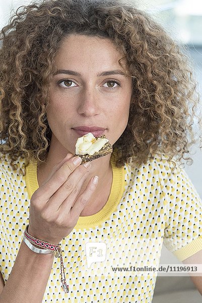 Close-up of a beautiful young woman eating bread with cheese