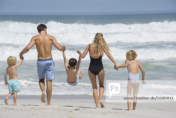 Rückansicht einer Familie beim Spaziergang am Strand