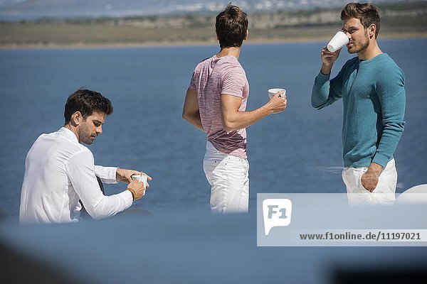Fröhliche männliche Freunde beim gemeinsamen Kaffeegenuss im Freien