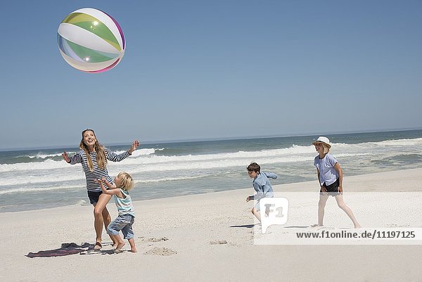 Schöne Frau spielt mit ihren Kindern Strandball