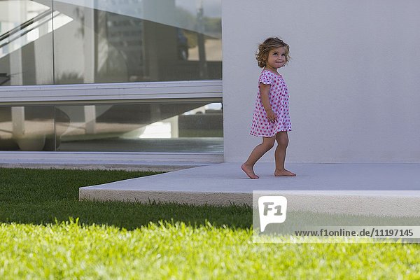 Kleines Mädchen beim Spielen im Hinterhof des Hauses