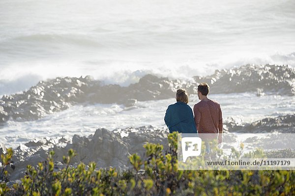 Glückliches Paar schaut auf das Meer am Strand