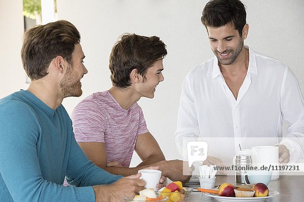Glückliche männliche Freunde beim Frühstück zu Hause