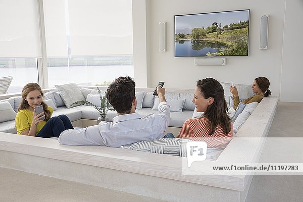 Couple watching television with their daughters busy in different activities