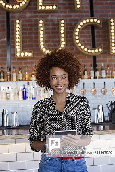 Portrait of happy young woman with a digital tablet at bar counter