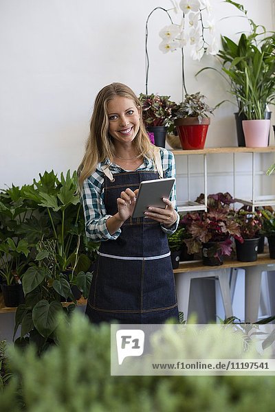 Porträt einer glücklichen Frau mit einem digitalen Tablett in ihrem Blumenladen