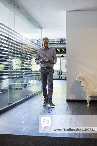 Businessman using a digital tablet in office hallway