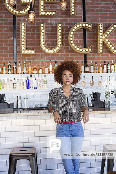 Portrait of a young woman standing at bar counter