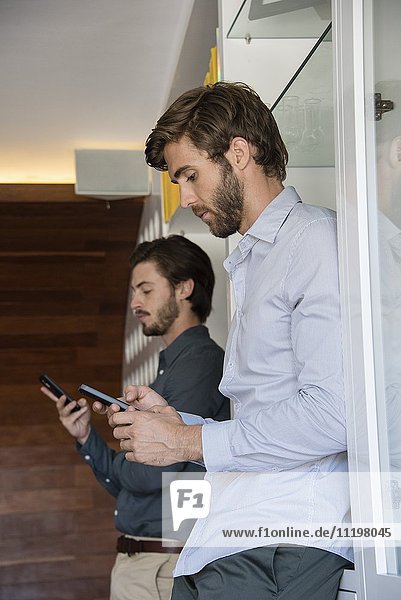 Zwei Geschäftsleute mit Mobiltelefonen im Büro