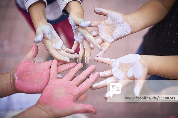 Hands of children covered in multicolor chalk