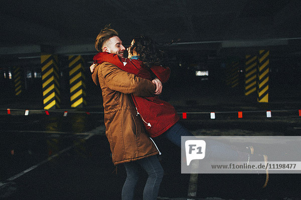 Caucasian couple hugging in parking garage