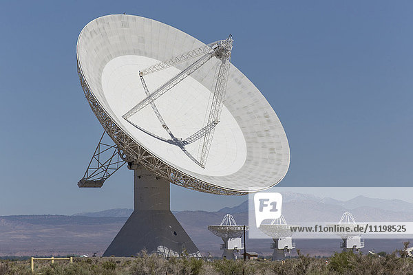 Satellite dishes in field near mountain range