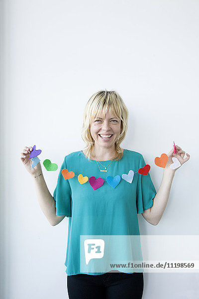Caucasian woman holding string of paper hearts