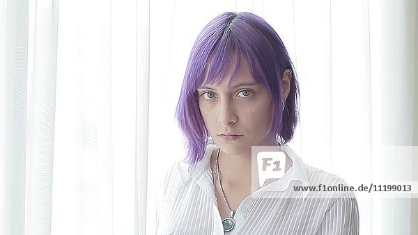 Porträt einer ernsten jungen Frau mit violettem Haar