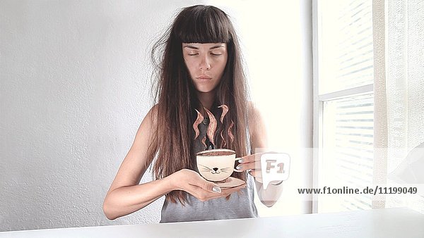 Junge Frau blinzelt mit den Augen und hält eine dampfende Tasse Kaffee