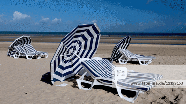 Blaugestreifte Liegestühle und Sonnenschirme am Strand