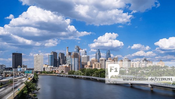 Zeitraffer von Autos und Zugfahrt auf beiden Seiten des Schuylkill River mit Skyline im Hintergrund  Philadelphia  Pennsylvania  USA