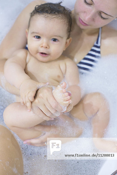 Mother and baby soaking in bathtub together