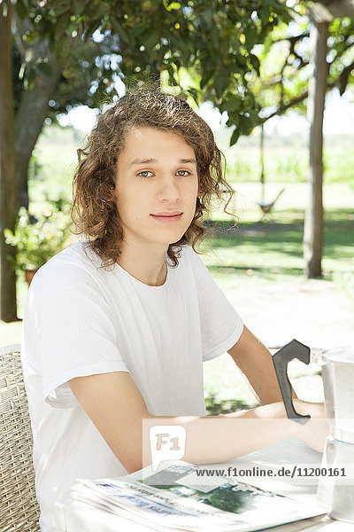 Junger Mann am Frühstückstisch im Freien