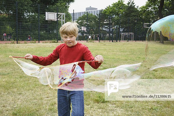 Junge spielt mit Seifenblasen im Park