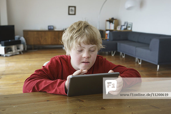 Behinderter Junge mit digitalem Tablett zu Hause