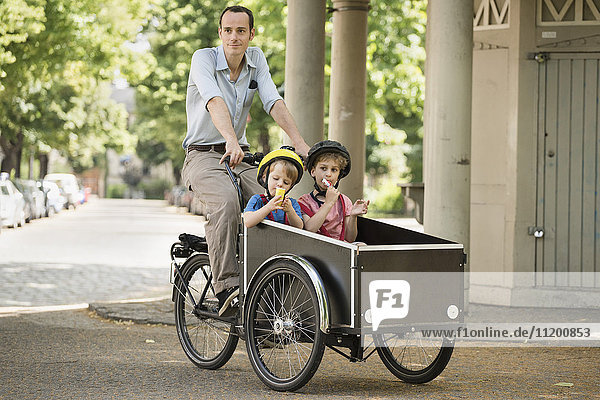 Vater mit Jungen Fahrrad fahren mit Karre auf der Straße