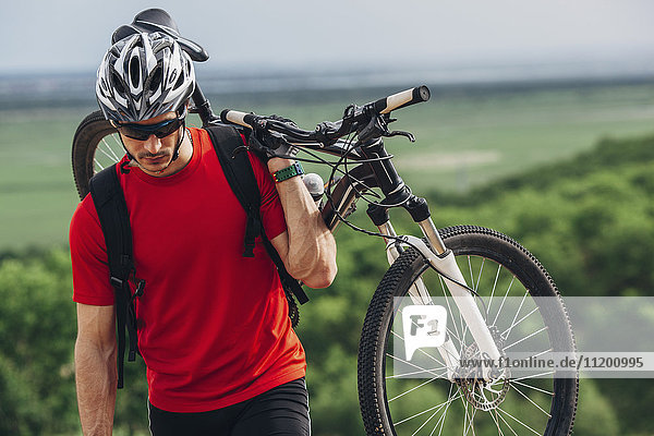Mountain biker carrying bicycle up hill