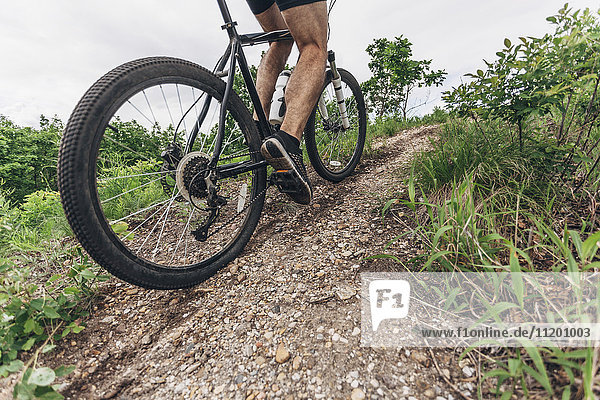 Low section of man riding mountain bike on dirt track